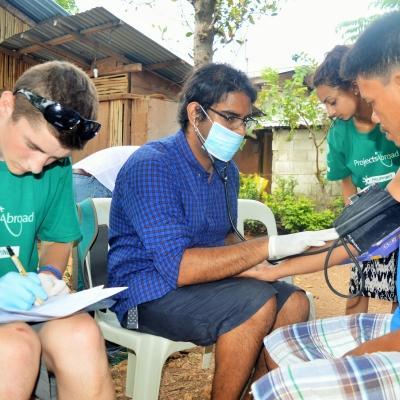 At a Public Health placement for teenagers in the Philippines, a student conducts vital sign medical checks during an outreach. As part of the Projects Abroad Public Health Internship for teenagers in the Philippines, student assists a local doctor during a medical outreach.